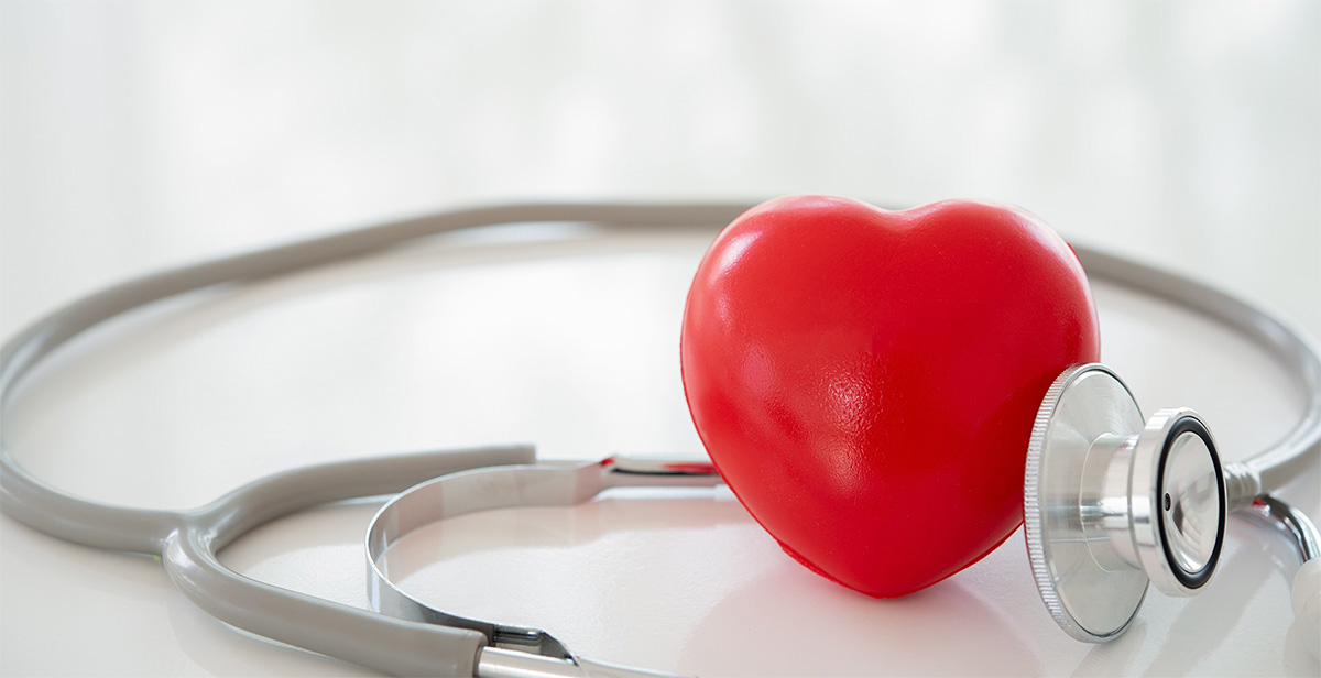 Ein Stethoskop lehnt sich leicht an ein rotes abstraktes Herz an.