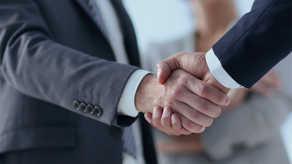 Zwei Personen geben sich einen gesch&auml;ftlichen Handschlag.