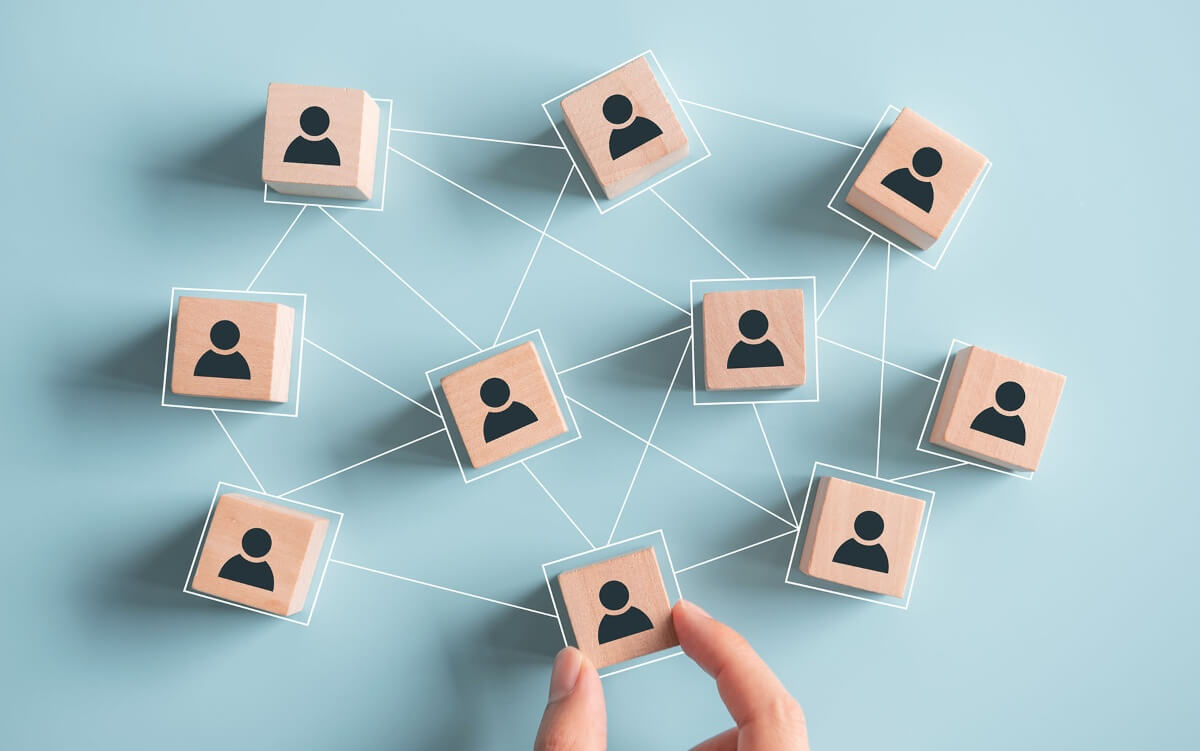 W&uuml;rfel mit Personen-Symbol drauf, die in einem Netz miteinander verbunden sind.