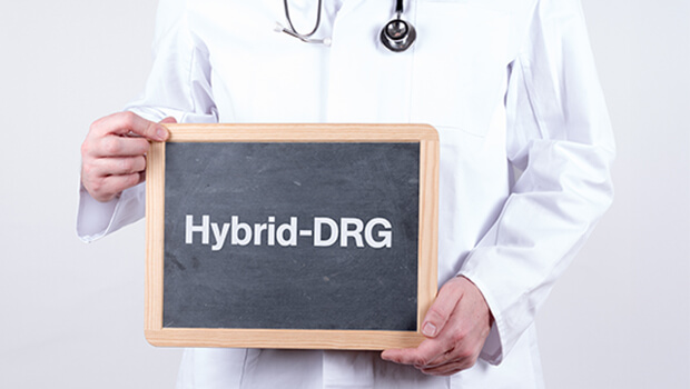 Ein Arzt h&auml;lt eine kleine tafel hoch, auf der "Hybrid-DRG" steht.