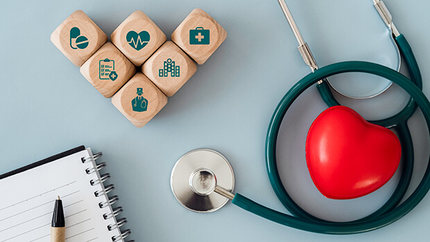 Stethoskop liegt neben Holzw&uuml;rfeln mit Krankenhaus-Symbolen drauf.