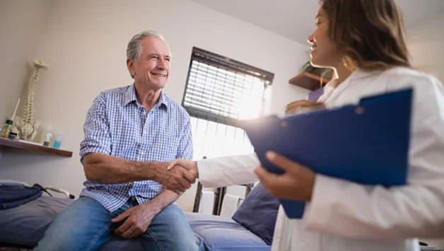 Eine &Auml;rztin sch&uuml;ttelt einem Patienten die Hand.