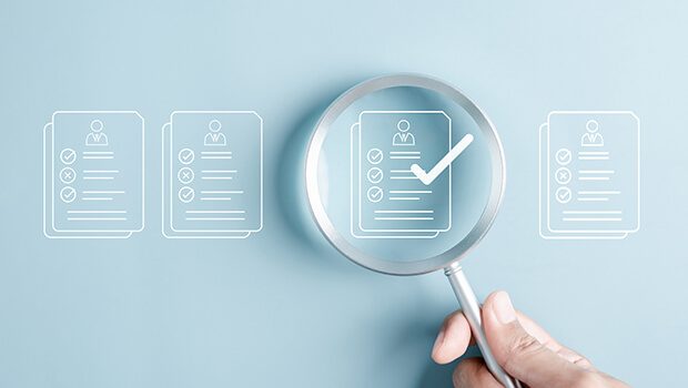 Mithilfe einer Lupe werden Dokumente nach ihrer Richtigkeit &uuml;berpr&uuml;ft.